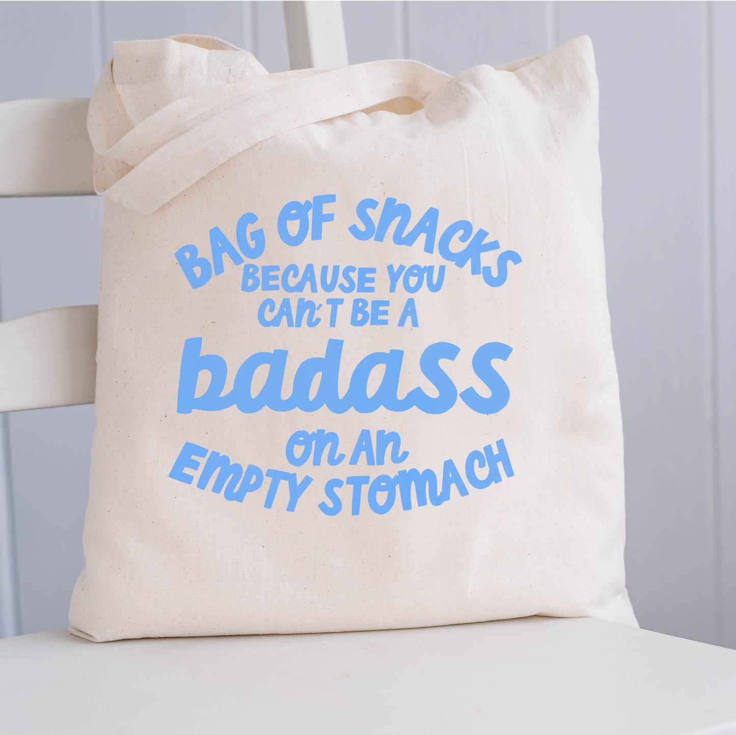 Natural Coloured Tote Bag featuring quote 'bag of snacks because you can't be a badass on an empty stomach' in blue writing