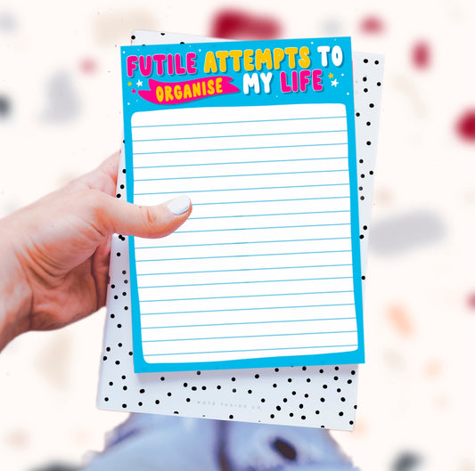 'Futile Attempts' Notepad: An energetic product image showcasing the quote "futile attempts to organise my life." Designed by Colourful Life, A5 size, tear-off sheets, and a sturdy cardboard backing for a burst of creative chaos.